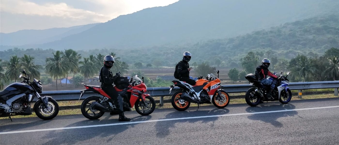 Photo de 3 personnes avec leur moto sur le bord d'une route